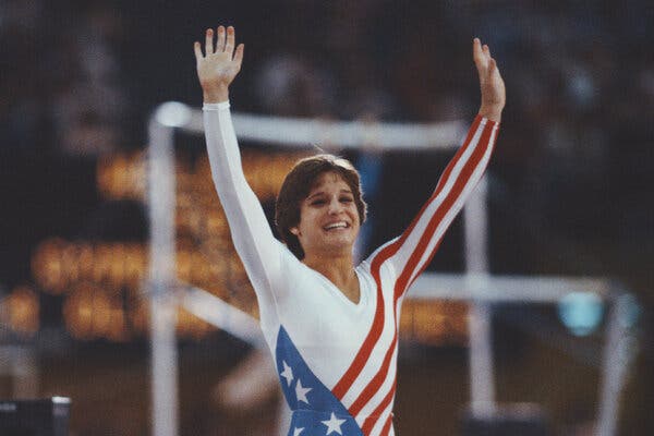 Mary Lou Retton raises her hands and smiles while competing in 1984.